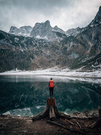 Executive standing on a mountaintop, looking out at water and mountains, symbolizing reflection and achievement in leadership.